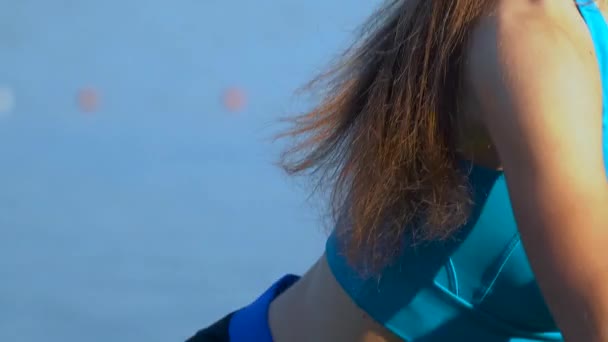 Młoda dziewczyna, ubrana w kombinezon sportowy, ma Split squat na wybrzeżu jeziora w lecie — Wideo stockowe