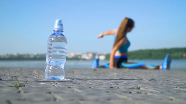 A rapariga está sentada num fio junto ao lago. Movimento lento. Água em primeiro plano — Vídeo de Stock