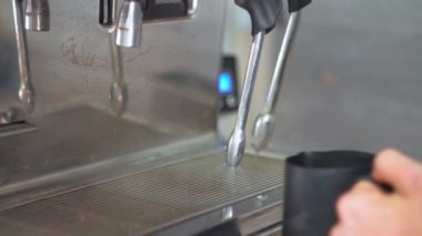 Kahve makinesinin özel bir tüp kullanarak bir blac kahve tencerede beyaz süt kırbaçlanan. Barda kahve yapmak