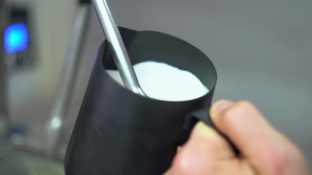 Chicotadas leite branco em uma panela de café blac usando um tubo especial da máquina de café. Fazendo café — Vídeo de Stock