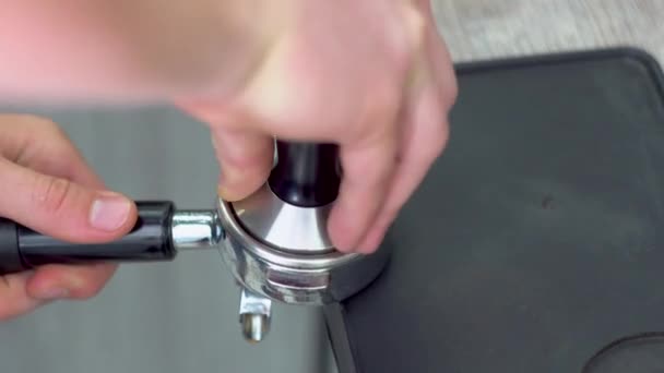 Att göra kaffe. En närbild av en hand som håller ett portafiltret med malet kaffe på kanten av bordet — Stockvideo