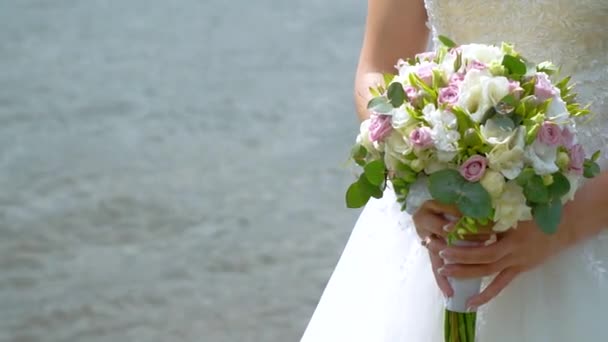 Bride holds bouquet of white and pink roses on flowing water background. Closeup of bouquet and hands. Moving frame — Stock Video
