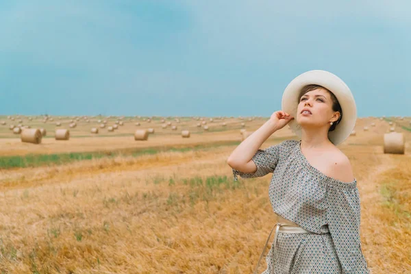 Şapkalı güzel kız, yaz akşamları balyalarıyla bir buğday tarlasının ortasında gökyüzüne bakıyor.