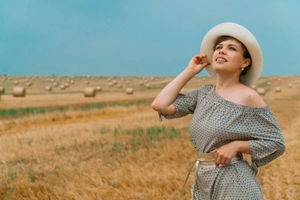 Şapkalı güzel kız, yaz akşamları balyalarıyla bir buğday tarlasının ortasında gökyüzüne bakıyor.