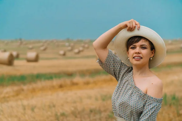 Şapkalı güzel kız, yaz akşamları balyalarıyla bir buğday tarlasının ortasında gökyüzüne bakıyor.