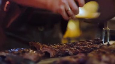 Aşçı domuz kaburgalarının ateşinde rosto baltasını keser. Izgara pirzola. Et yemeklerinin estetik hizmeti