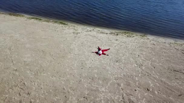 O Pai Natal está deitado na praia. Vista superior. Câmera se move para a linha d 'água — Vídeo de Stock