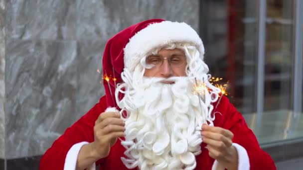 Papai Noel senta-se perto do edifício de escritórios da cidade e detém sparklers. Santa em Nova Iorque — Vídeo de Stock
