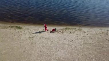A Christmas tree and a gift bag fall from the sledges onto the sand. Santa Claus Tired and he doesnt care that he lost his gift bag and Christmas tree