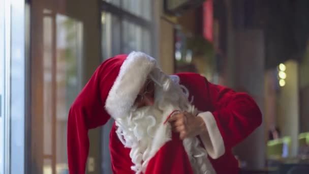 Santa Claus hledá něco v její dárkové tašce — Stock video