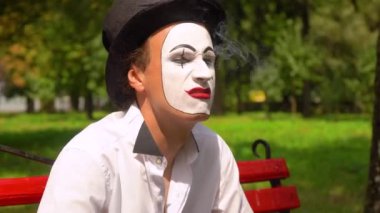 Bir pandomimcinin yakın çekimi açık havada sigara içer. Kötü alışkanlıklar.