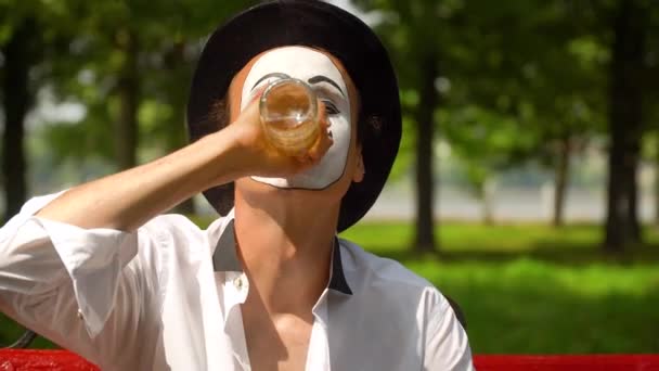 Close-up of a mime drinks alcohol outdoors. Bad habits — Stock Video