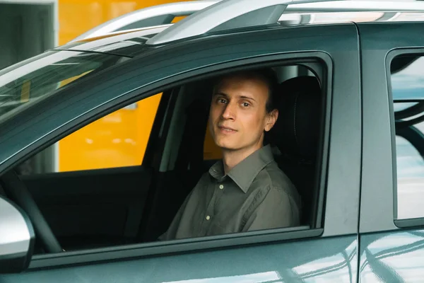 Un hombre con una ropa casual inteligente se sienta en un coche — Foto de Stock