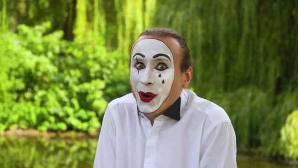 Fun mime looking at the camera and smiling on green background in a park. Emotion of joy — Stock Video