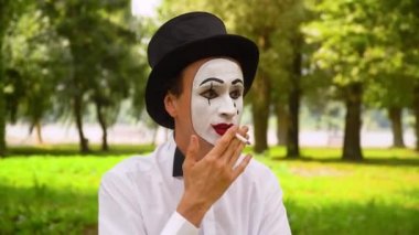 Siyah şapkalı pandomimci dışarıda sigara içiyor. Kötü alışkanlıklar.