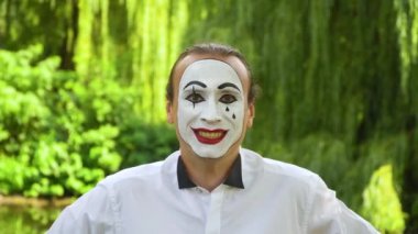 Kameraya bakıp yeşil arka planda gülümseyen eğlenceli pandomimci.