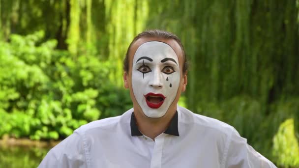Close-up of a mime looking at the camera enthusiastically on green background in a park. Emotion of wonder — Stock Video