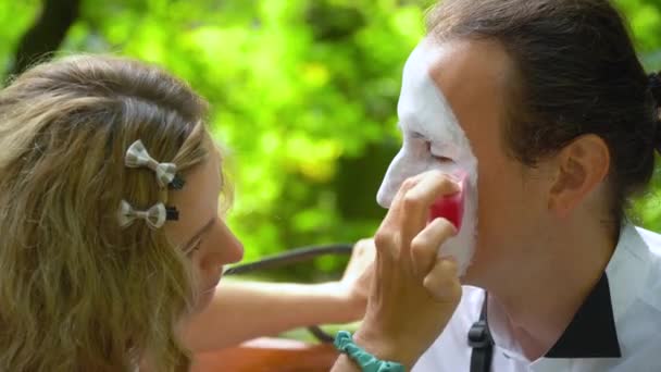 Fille peinture visage à jeune homme mime avec — Video