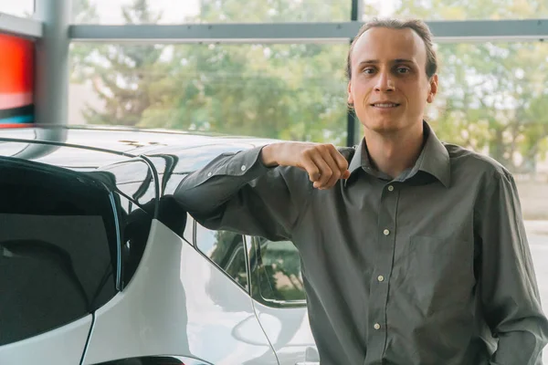 Un hombre con ropa clásica se para en una exposición de coches en el fondo de un coche — Foto de Stock