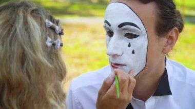 Kız kırmızı kalemle pandomimciye dudak boyuyor