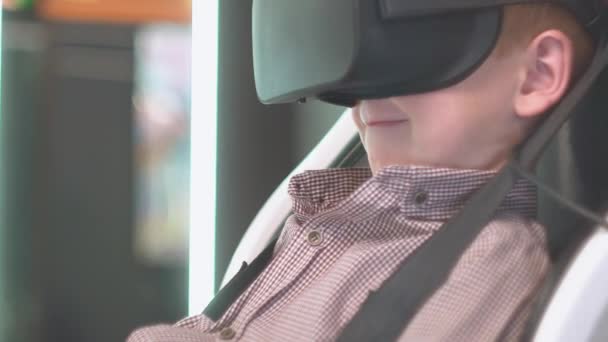 A boy with red hair wearing virtual reality glasses sits in the seat of a virtual reality set — Stock Video
