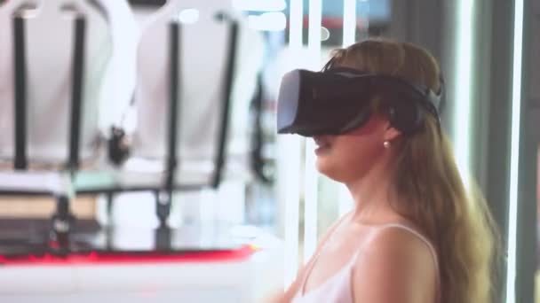 Młoda dziewczyna w okularach wirtualnej rzeczywistości odgania wirtualne rzeczy machając rękami — Wideo stockowe