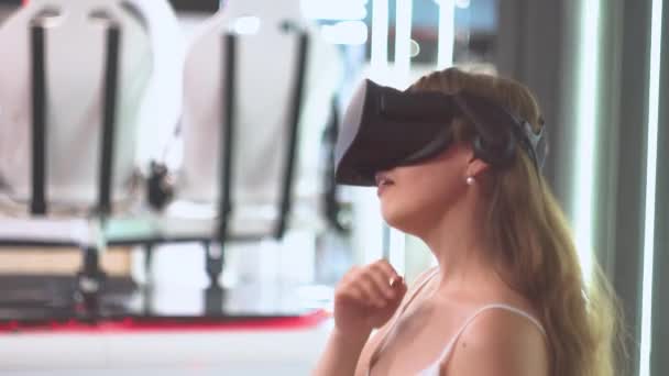 Ung flicka i virtual reality glasögon jagar bort virtuella saker genom att vifta med händerna — Stockvideo