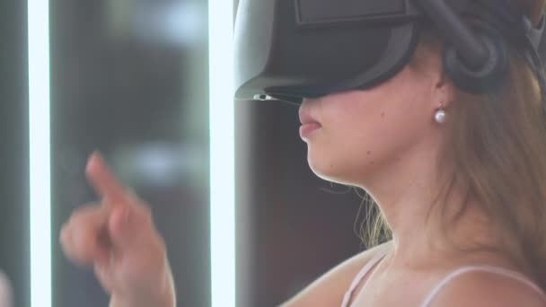 Uma jovem em óculos de realidade virtual mantém uma linha imaginária na forma de um círculo — Vídeo de Stock