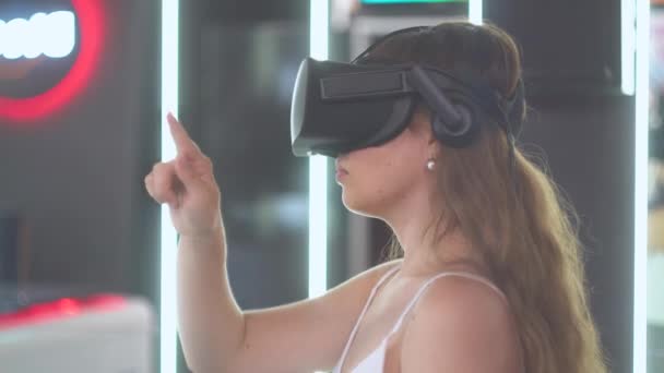 Een jong meisje in virtual reality bril houdt een hand in de vorm van rechte en golvende lijnen — Stockvideo