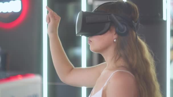 Ung flicka i virtual reality glasögon håller en imaginär vertikal linje med handen — Stockvideo