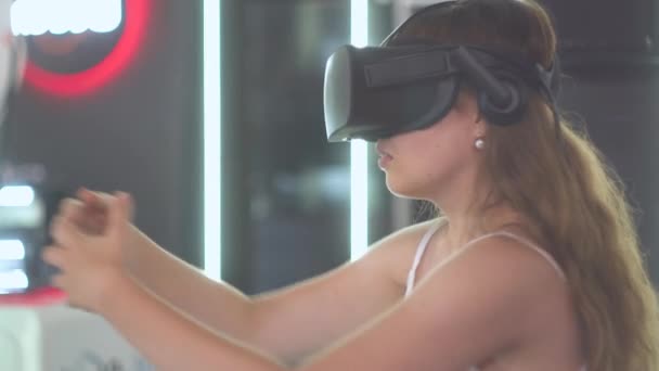 Ung flicka i virtual reality glasögon gör rörelser med händerna som om dra upp något för sig själv — Stockvideo