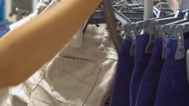 Kadın mağazadaki erkek için pantolon seçiyor. Ellerin yakın görüntüsü