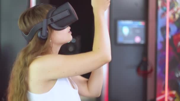 Una joven con gafas de realidad virtual hace gestos de manos como si tirara de una cuerda — Vídeo de stock