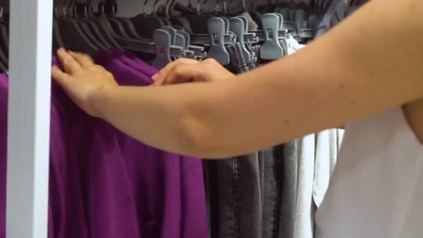 A nő a kötött pulóvereket választja a boltban. Közelkép a kezekről — Stock videók