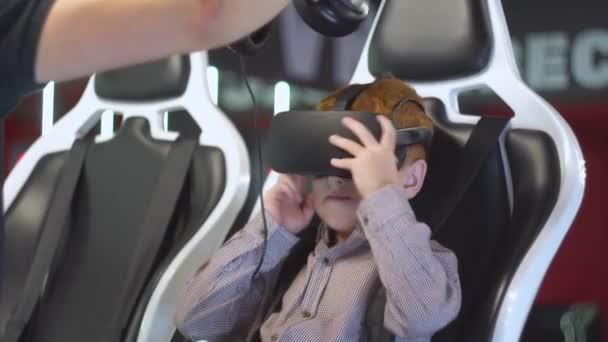 Assistant porte des écouteurs sur la tête des petits garçons pour jouer ensemble de réalité virtuelle — Video