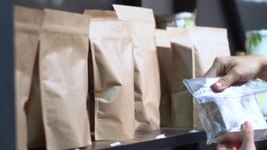Bir kadın el sanatları paketlerinde paketlenmiş bir ürün seçer. Alıcı ve ürün işçilerinin yakın görünümü