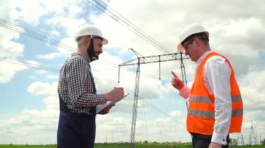 İletişim hatları yakınında çalışan iki mühendis. Menajer aktarım hatlarının yakınında görev veriyor. Elektrik direkleri