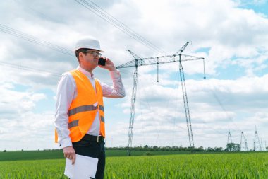 İletişim hatlarının yakınında çalışan bir mühendis. Elektrik mühendisi yüksek voltaj hatlarını kontrol ediyor. Aktarım kuleleri