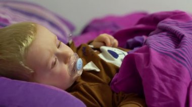 Hasta çocuk yatakta bir termometreyle yatıyor.