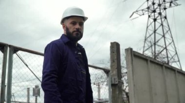 Elektrik santralinin yakınında çalışan bir mühendis. Enerji verimliliği kavramı. Aktarım kuleleri