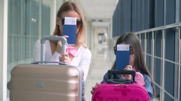 Mujer y niña sosteniendo pasaportes y billetes de avión. Tarjeta de embarque y pasaporte en el aeropuerto. Esperando la llegada de la aeronave — Vídeo de stock