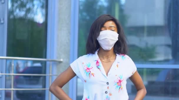 Chica afroamericana se pone una máscara médica para la prevención del coronavirus y mirando a la cámara. Protección Covid-19. Detener virus — Vídeo de stock