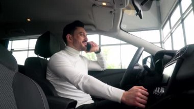 Araba galerisi müdürü araba satmayı kabul etti. Satıcı, yeni bir arabada oturan telefonla işlemin detaylarını tartışır
