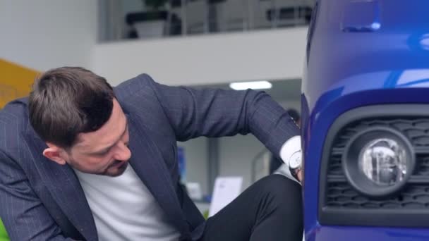 Homem elegante inspeciona um carro novo em uma concessionária de carros — Vídeo de Stock