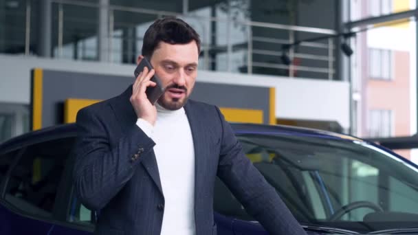 L'uomo d'affari sta parlando al telefono nello showroom dell'auto. Concetto vendita auto — Video Stock