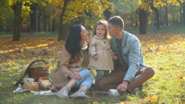 Mãe e pai com a filha se divertindo ao ar livre. Piquenique no parque de outono — Vídeo de Stock