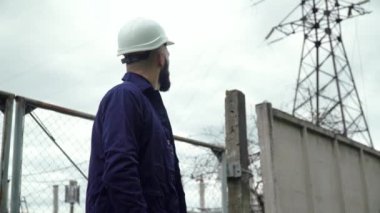 Özel üniformalı mühendis güç istasyonunun yanında tabletle bekliyor. Enerji verimliliği kavramı