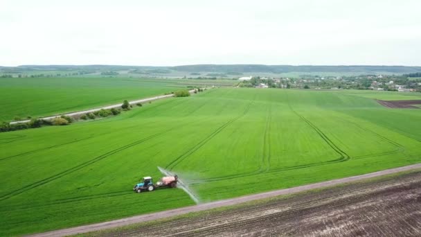 Vista aérea de la pulverización de tractores agrícolas en el campo con pulverizador, herbicidas y pesticidas — Vídeo de stock