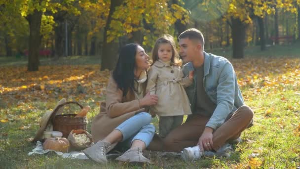 Mãe e pai com a filha se divertindo ao ar livre. Piquenique no parque de outono — Vídeo de Stock