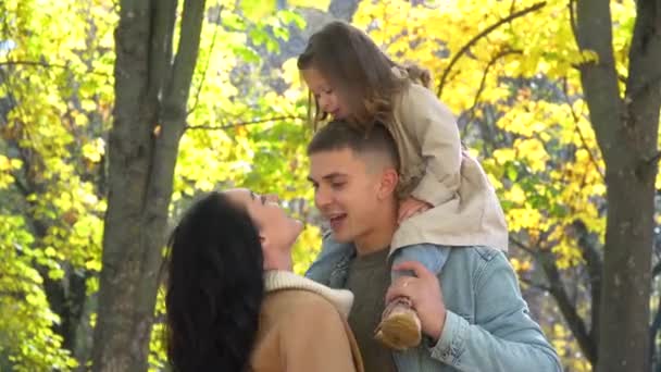 Дитина на спині батька. Щаслива родина в осінньому парку. Падіння — стокове відео